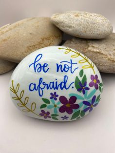 a painted rock with the words, be not afraid on it and some rocks behind it