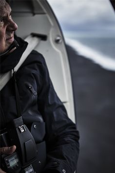 an older man holding a camera in his left hand and looking out the window of a boat