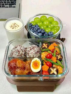 two plastic containers filled with food next to a cup of milk and a laptop computer