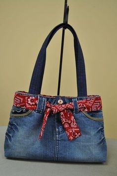 a denim purse with a red bandana bow on the front and side pocket, hanging from a hook