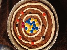 a cookie cake with white frosting and colorful candies in the shape of a spiral