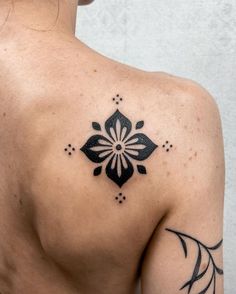 the back of a woman's shoulder with black and white tattoos on her chest