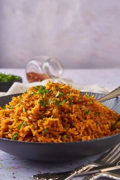 a bowl filled with rice and garnished with parsley next to silverware