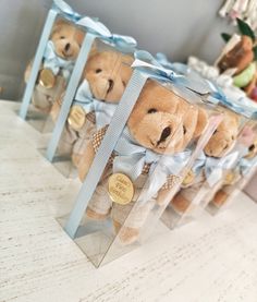 four clear boxes with teddy bears in them sitting on a white countertop next to other stuffed animals