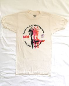 Head back to the summer of '84 in Los Angeles with this great Olympics torch t-shirt. Never worn! Soft and thin off-white poly cotton with flattering fit. Made in USA.Label: MCA/FMI '84 Fabric: 50% polyester/50% cotton Size: SmallCondition: ExcellentMeasurements:Front (base of collar to bottom): 22”Back (base of collar to bottom): 25”Shoulder: 13Sleeve: 7.25”Chest (armpit to armpit): 15”Sleeve opening: 3.25”Sleeve opening (stretched): 4.75” Los Angeles Summer, Best Books For Men, Philanthropy Shirts, Retro Logos, Vintage Crewneck, Summer Olympics, 80s Retro, Vintage Branding, Fancy Dresses