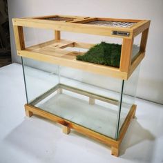 a display case with grass in it sitting on a white tablecloth covered flooring