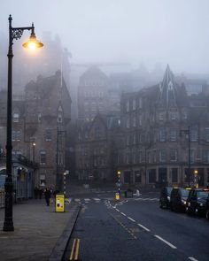 a foggy city street with cars parked on the side