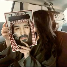 a man with long hair and beard holding up a photo in the back seat of a car