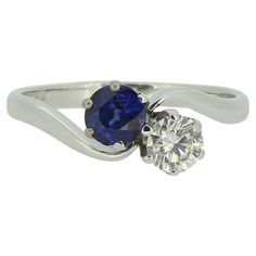 a white gold ring with a blue sapphire and two diamonds