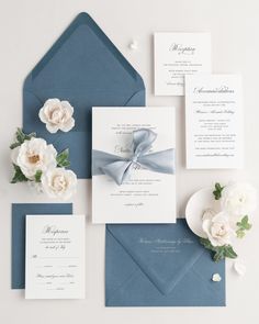 the wedding stationery is laid out on top of an envelope, with white flowers and greenery