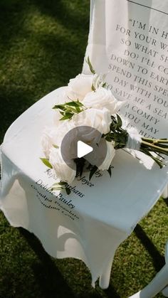 a white chair with flowers on it sitting in the grass