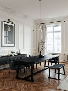 an elegant dining room with wood flooring and white walls, along with black chairs