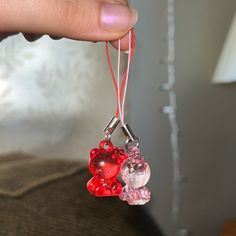 a person is holding a red and pink teddy bear keychain in their hand