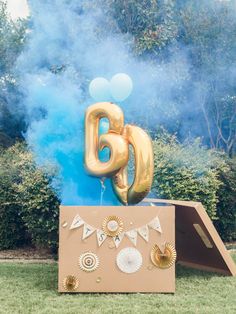 an air filled balloon that says sixty is on top of a cardboard box in the grass