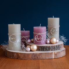 three candles sitting on top of a wooden table next to christmas ornaments and baubles