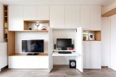 a living room with white walls and built - in shelving units, including a flat screen tv