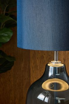 a black lamp with a blue shade on it next to a potted green plant