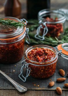 two jars filled with food sitting on top of a wooden table next to spoons