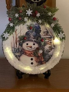 a lighted snowman plate on top of a wooden table with a clock in the background