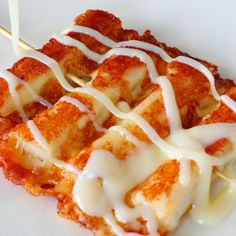 some kind of food on a white plate with toothpicks in it and sauce drizzled over the top