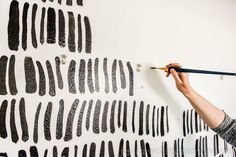 a woman is painting on the wall with black paint