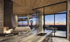 a modern kitchen and living room with large windows overlooking the mountains at sunset or dawn