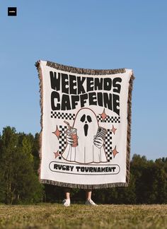 a person standing in the grass holding a sign that says weekend's caffeine