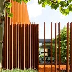 an orange building with wooden slats on the front and side walls, surrounded by trees