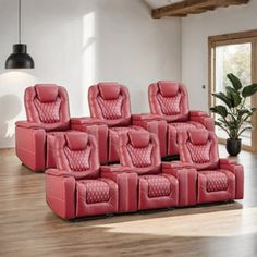 a group of red recliner chairs sitting in a living room next to a potted plant