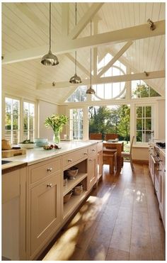 a large kitchen with wooden floors and white walls, has an island in the middle