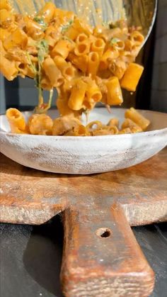 a spoon full of macaroni and cheese is being lifted from a white bowl