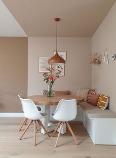 a dining room table with white chairs and a bench in front of the table,