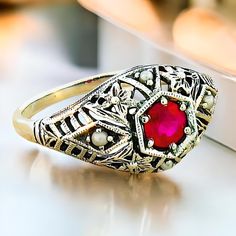 Discover a stunning piece of elegance with our Vintage Natural Ruby and Freshwater Pearl Accent Filigree Ring, meticulously crafted to elevate your jewelry collection. This exquisite ring features a vibrant, deep red natural ruby, surrounded by dainty freshwater pearls that gently complement its allure. Each ring is expertly crafted in quality 925 solid sterling silver, ensuring a timeless piece that shines with sophistication. The intricate filigree design showcases the artistry and attention to detail that defines exceptional vintage jewelry, making it a perfect choice for both everyday wear and special occasions. Whether you're dressing up for a night out or adding a touch of glamour to a casual outfit, this unique ring will surely draw admiration. To maintain its brilliant shine and be Formal Sterling Silver Birthstone Ring With Accent Stones, Victorian Pearl Ring Gemstone Gift, Victorian Pearl Ring With Gemstone For Gift, Victorian Pearl Ring Gift, Victorian Style Pearl Ring Gift, Elegant Cluster Ring With Intricate Design For Anniversary, Elegant Anniversary Cluster Ring With Intricate Design, Formal Sterling Silver Birthstone Ring, Elegant Sterling Silver Formal Birthstone Ring