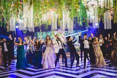 a group of people standing on top of a floor next to each other in front of chandeliers