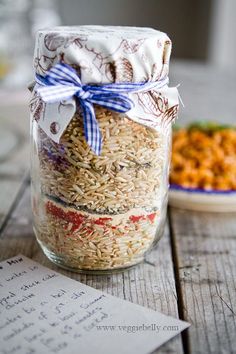 a glass jar filled with rice next to a plate of food on top of a wooden table