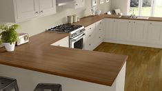 a kitchen with white cabinets and wooden counter tops, along with two stools in front of the stove