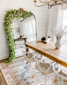 a dining room table with chairs and a cat laying on it's back in front of a mirror