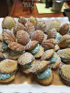 a white platter filled with pastries covered in powdered sugar and blue icing