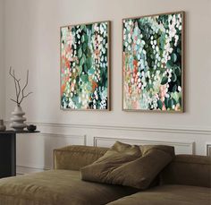 two paintings hang on the wall above a couch