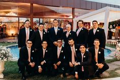 a group of men standing next to each other in front of a swimming pool wearing suits and ties