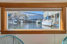 there is a boat docked at the dock in the water near two chairs and a window