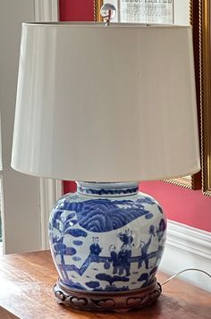 a blue and white vase sitting on top of a wooden table next to a lamp