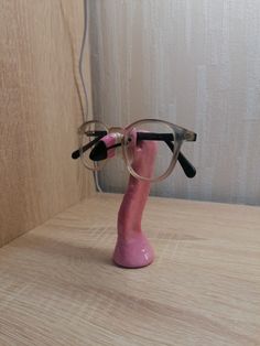 a pair of glasses sitting on top of a wooden table next to a pink object