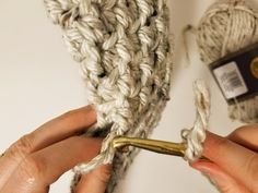 two hands are crocheting the ends of a rope with gold pliers in front of them