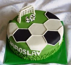 a soccer themed birthday cake on top of a green tableclothed sheet with white and black decorations