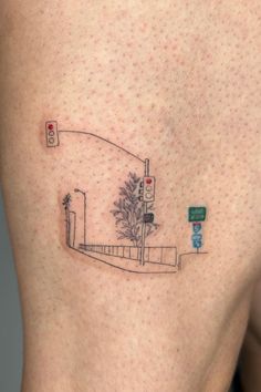 a small tattoo on the side of a woman's thigh shows a tree and street signs