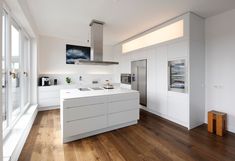 a kitchen with white cabinets and wood flooring next to a large glass door window