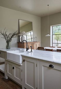 a kitchen with white cabinets and an island in the middle is seen from across the room