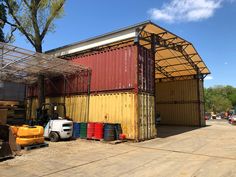 an outdoor storage shed with several containers in the foreground and two forklifts on the other side