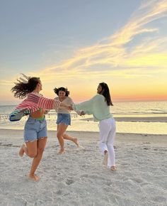 three young women are playing on the beach at sunset with their arms around each other